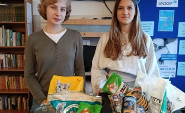 dwie  stojące osoby trzymają karmę dla zwierząt ze zbiorki  charytatywnej