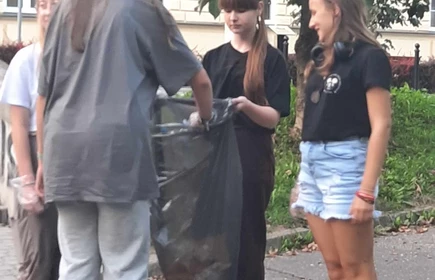 uczniowie wrzucający śmieci do worka