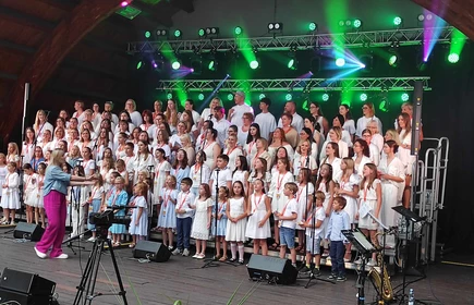 artyści ubrani na biało śpiewający piosenki