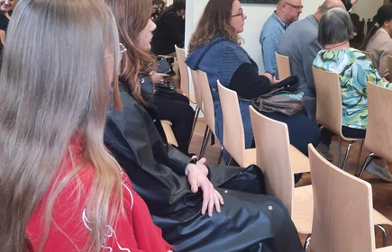 publiczność siedząca na krzesłach w sali