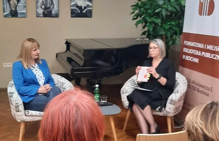 dwie panie siedzące na fotelach w sali bibliotecznej
