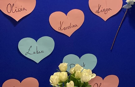 Na tablicy widać napis &bdquo;Już za krok matura&hellip; Żegnamy naszych maturzyst&oacute;w&rdquo;. Pod nim są kolorowe papierowe serca z imionami, a całość ozdobiona jest kwiatami po bokach. Przed nią stoi st&oacute;ł na kt&oacute;rym widać wazon z białymi r&oacute;żami