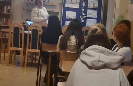 Stojąca wykładowczyni przed siedzącymi uczniami w ławkach