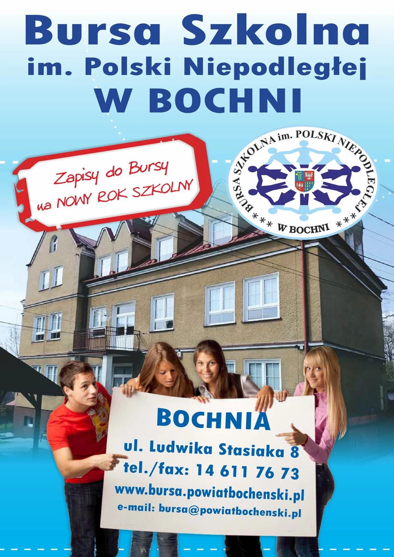  uczeń i trzy uczennice trzymajacy plakat na którym  widnieje napis z adresem i telefonem  Bursy ,za nimi widoczny jest budynek Bursy