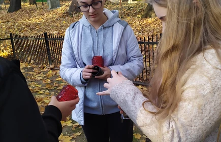 uczniowie zapalają świece na pomnik