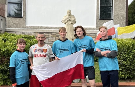 uczniowie uczetniczący w biegu z flagą Polski