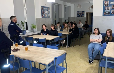 siedzące osoby przy stołach słuchające prelekcji