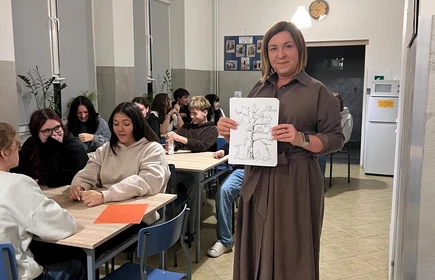 Stojący nauczyciel trzymający kartkę obok siedzących uczniów w ławkach