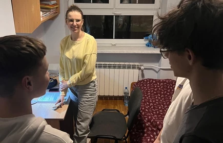 dw&oacute;ch chłopc&oacute;w stoi a przed nimi usmiechnięta dziewczyna