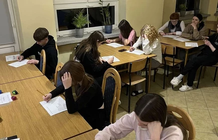 uczennice siedzące przy stole piszące na kartkach
