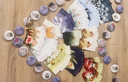 na zdjeciu widac drewniany blat na kt&oacute;rym w ksztacie sercasą ułozone okrągłe przypinki lub żetony a obok  kolorowe karty 