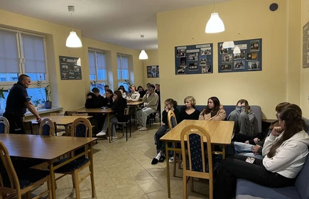 Uczniowie siedzący w sali i słuchający wykłady
