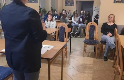 uczniowie siedzący w sali i słuchający wykładu