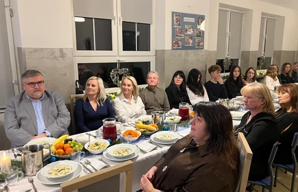 st&oacute;ł wigilijny przy ktoeym siedzą osoby dorosłe i młodziesz szkolna