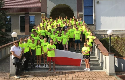 Zdjęcie grupowe uczestników biegu na schodach z flagą Polski 