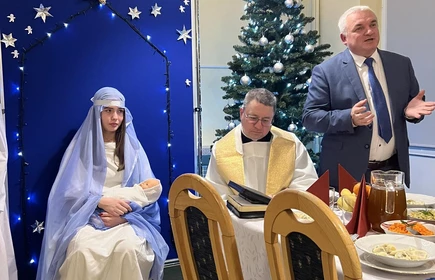 dyrektor bursy przemawiający do siedzących przy stole wigilijnym