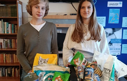 dwie  stojące osoby trzymają karmę dla zwierząt ze zbiorki  charytatywnej