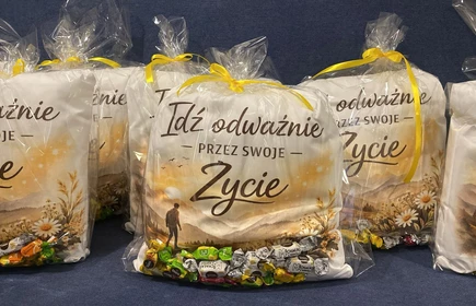 na zdjęciu widać kilka poduszek z napisem idź odważnie przez swoje życie zapakowane w przeźroczystą folię przewiązaną ż&oacute;łtą wstążką