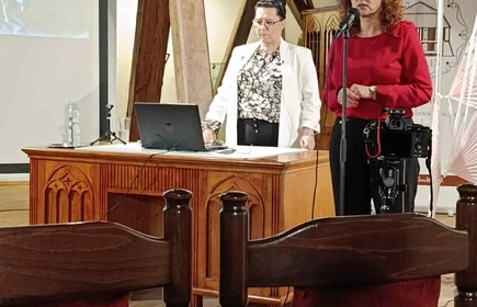 dwie stojące kobiety w trakcie wykładu