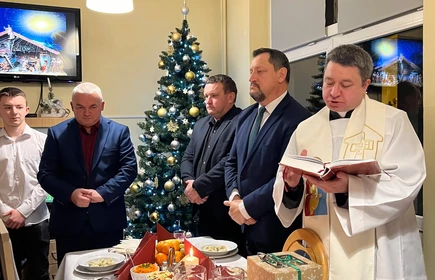 prowadzącu modlitwę wigilijna ksiądz i modlący się na stojąco dyrektor, wychowankowie, starosta i przewodniczący Rady Powiatu 