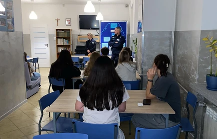 osoby siedzące przy stołach słuchające przemówień specjalistów 